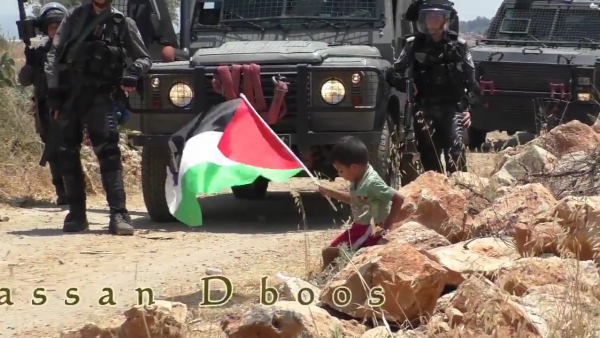 Palestinian child pushed towards soldier video screen shot sitting on rock